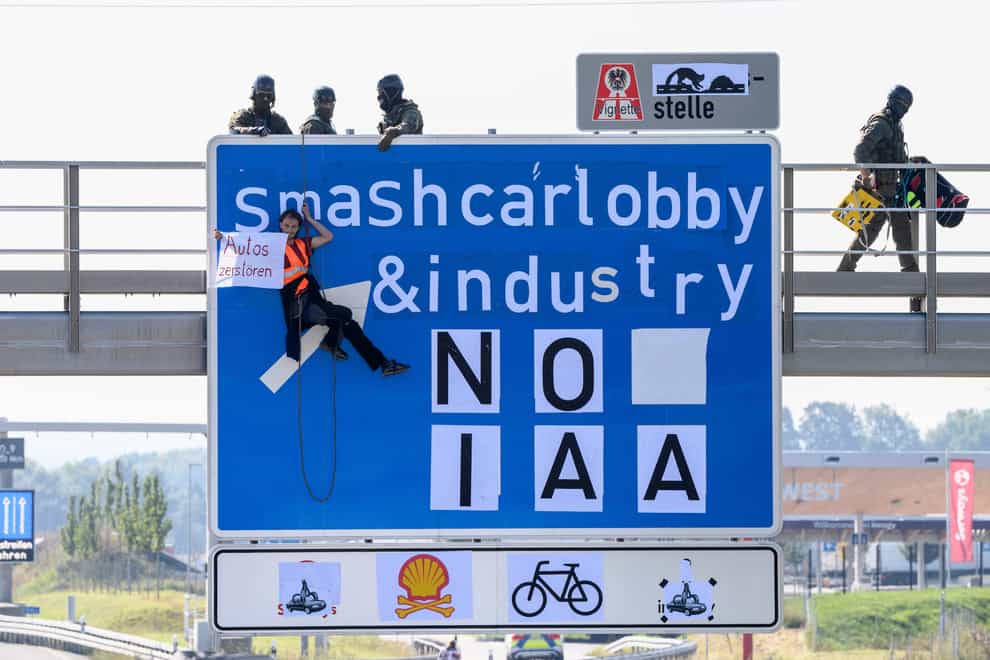 An activist hangs from a gantry over the A9 motorway near Furholzen in the direction of Munich during a banner campaign (dpa/AP)