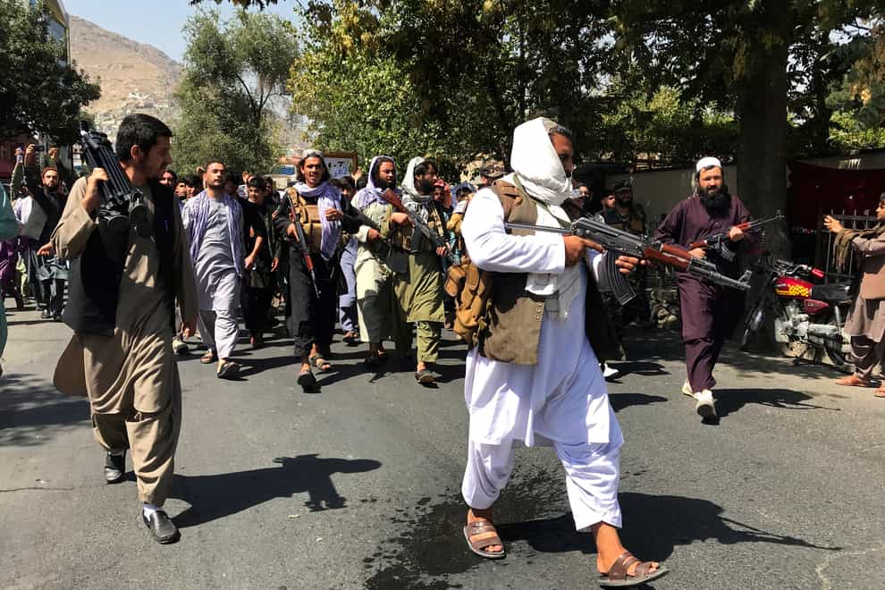 Taliban soldiers walk towards Afghans during a protest in Kabul (AP)