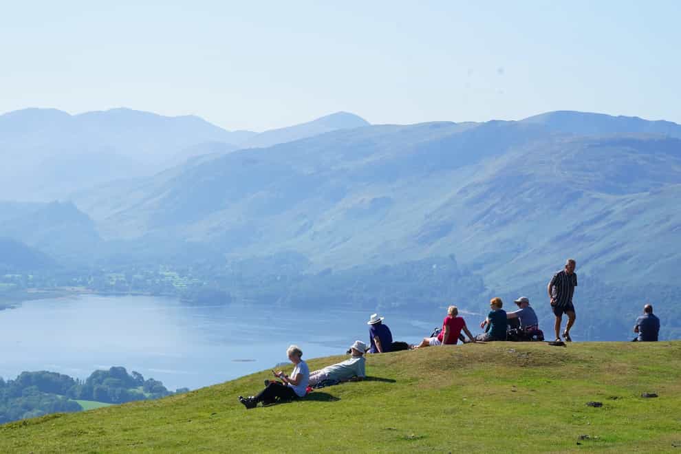 Walkers take in the view of Derwent Water in Cumbria (PA)