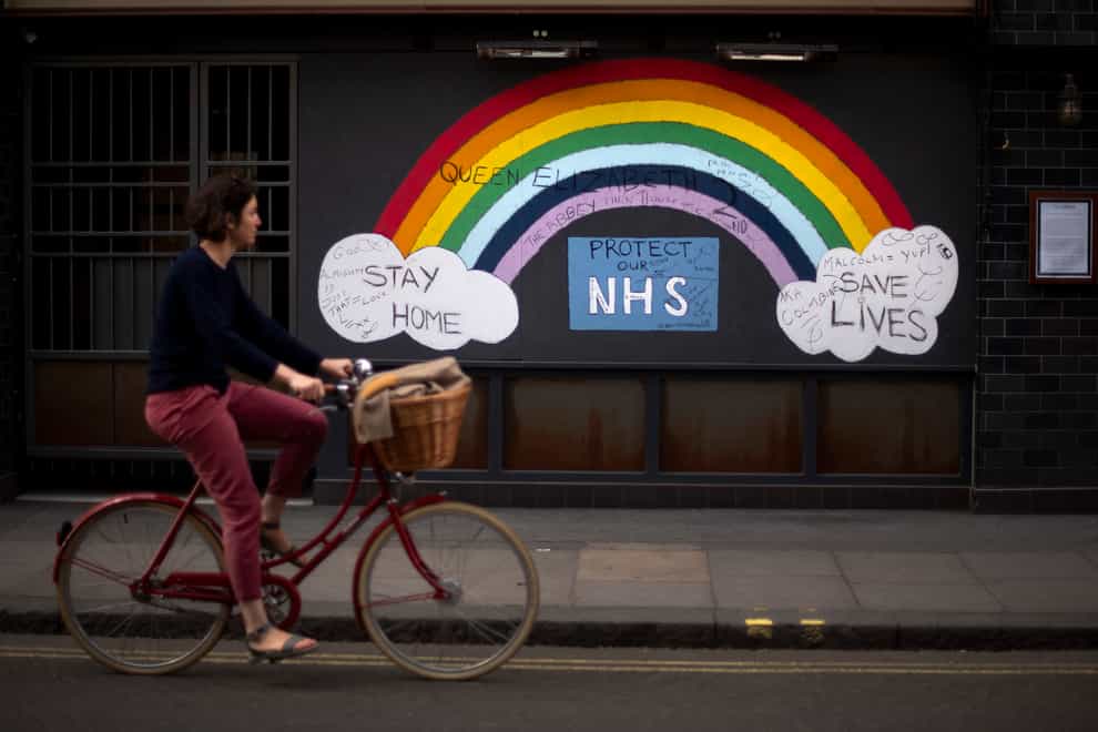 A woman cycles past a rainbow graffiti in support of the NHS in Soho (PA)