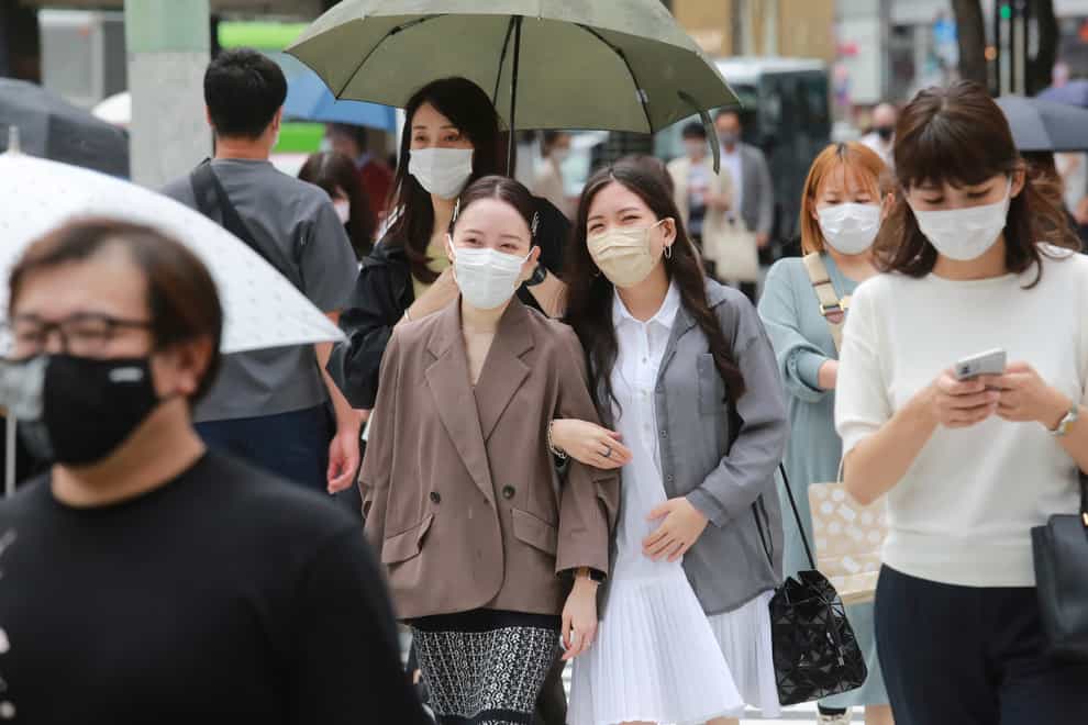 People wearing face masks to protect against the spread of coronavirus walk on a street in Tokyo (Koji Sasahara/AP)