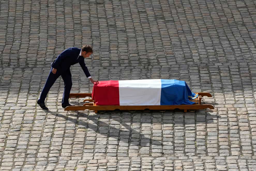 French President Emmanuel Macron touches the coffin of Jean-Paul Belmondo (Michel Euler/AP)