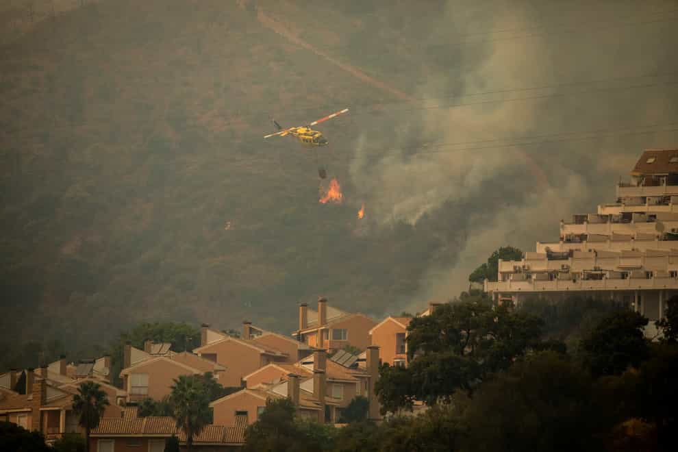 A helicopter makes a water drop over a wildfire in Estepona, Spain (AP Photo/Sergio Rodrigo)