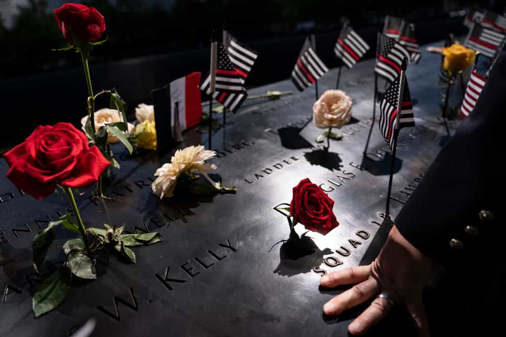 A firefighter places his hand on the names engraved on the September 11 memorial (AP)