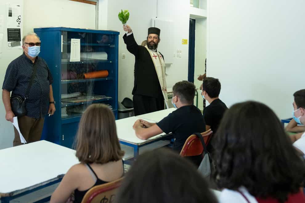 A Greek Orthodox priest blesses students in a classroom of a junior high school in Athens (Petros Giannakouris/AP)