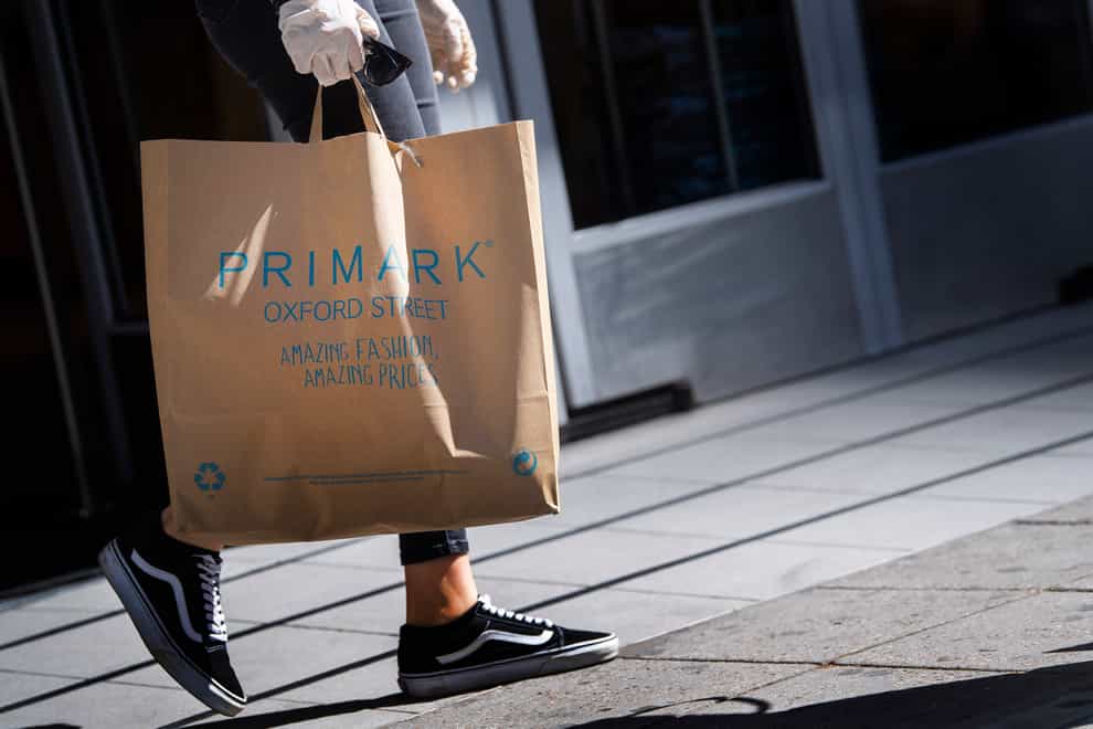 A customer carries bags of shopping as they leave Primark in Oxford Street (Victoria Jones/PA)