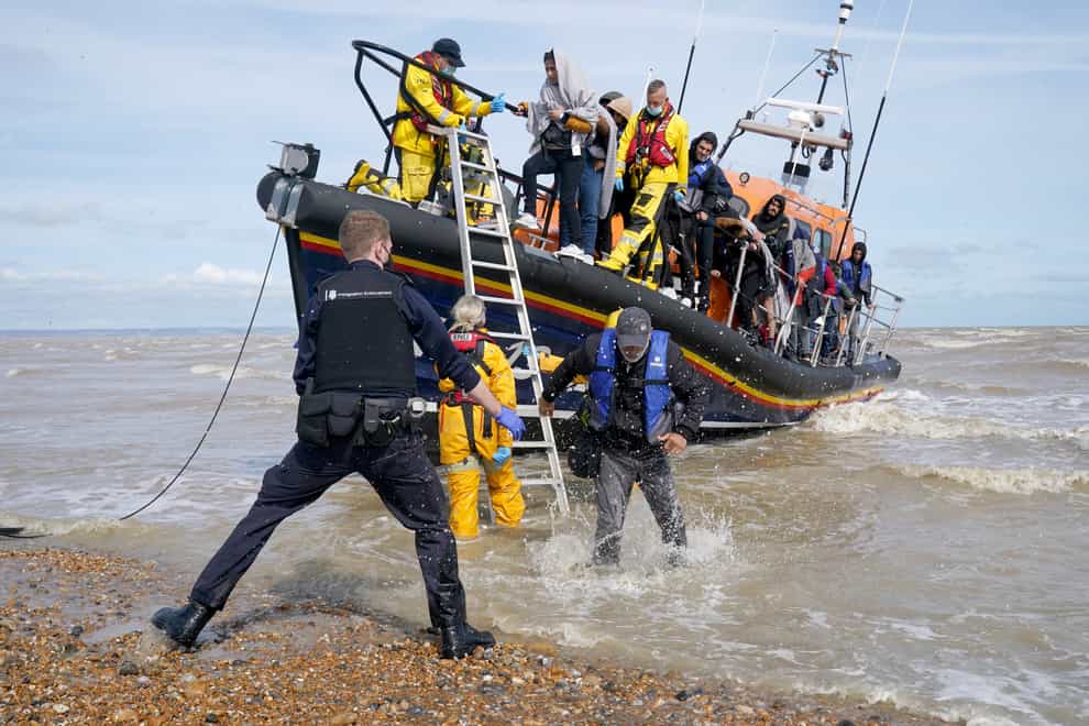 Immigration Enforcement officers and members of the RNLI assist a group of people thought to be migrants from an RNLI lifeboat after they were brought into Dungeness, Kent (Gareth Fuller/PA)