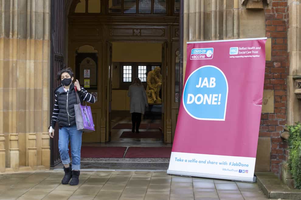 A woman walks past a Covid-19 sign at Queen’s University, Belfast (Liam McBurney/PA)