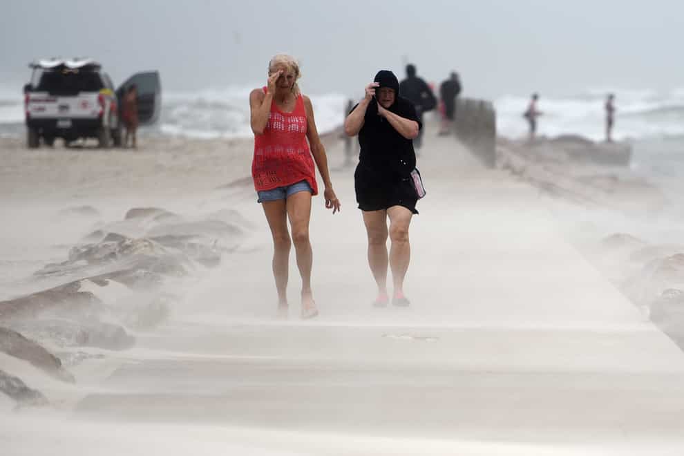 People in Texas shield their faces from wind and sand ahead of Hurricane Nicholas (Annie Rice/Corpus Christi Caller-Times via AP)