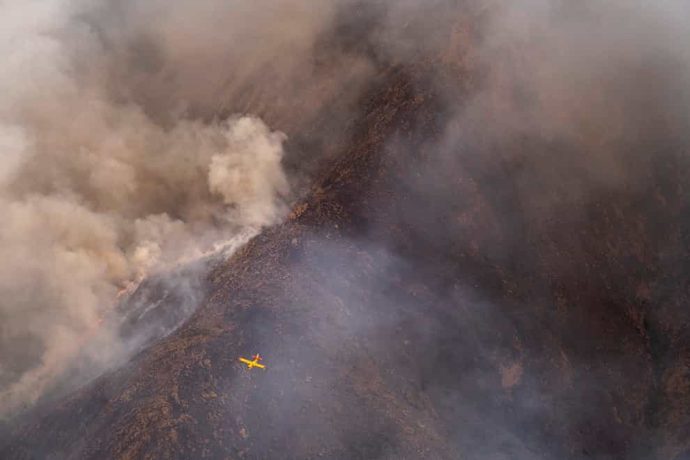 A seaplane flies over a wildfire in southern Spain (Pedro Armestre/AP)