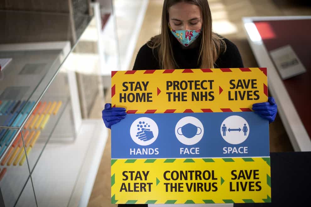 A staff member holds three signs from the Downing Street briefings (PA)