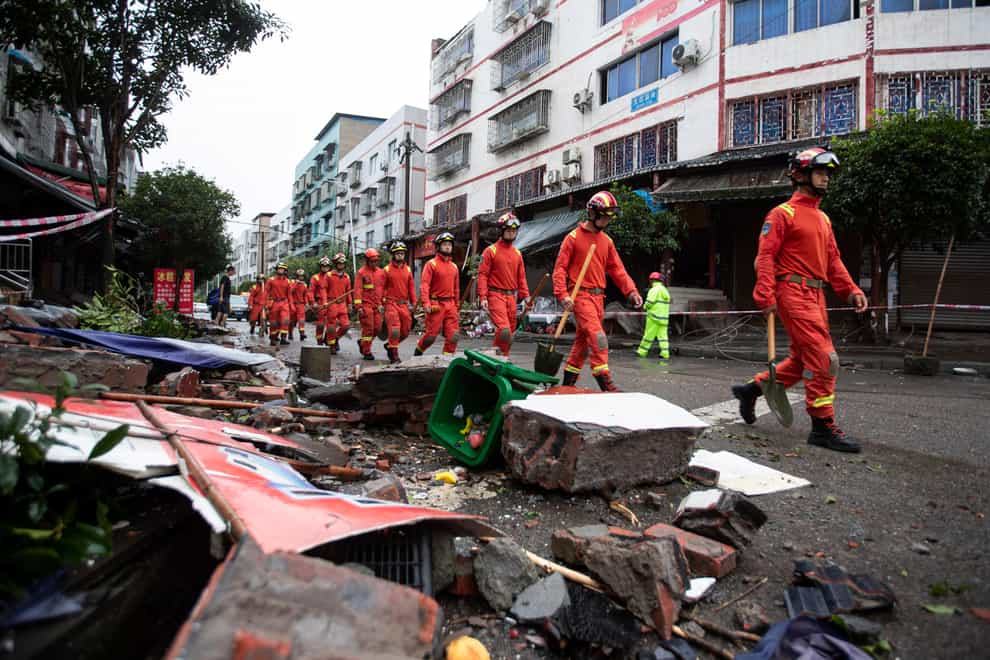 Rescue workers walk near debris in Luxian in the aftermath of the earthquake (Jiang Hongjing/Xinhua via AP)