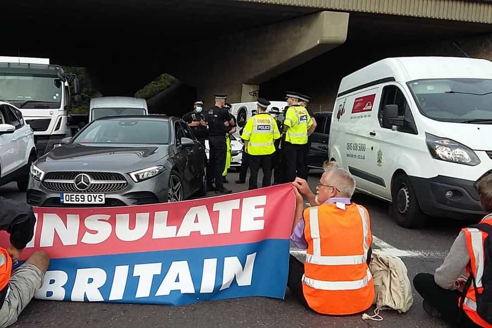 Police speaking to one another as protesters block an M25 junction on Monday (Insulate Britain/PA)