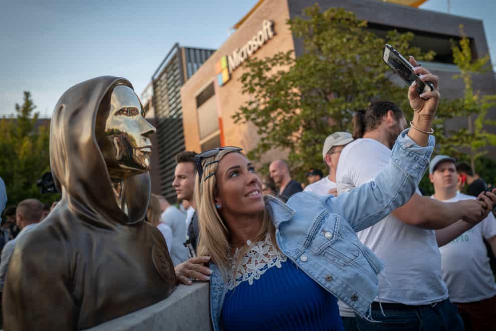 A woman takes a selfie with a newly unveiled statue of the mysterious developer of the Bitcoin digital currency in Budapest, Hungary (Bela Szandelszky/AP)