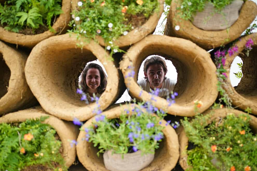 Designers Finbar Ward and Tilly Dallas look through bee hives formed from cylinders of clay, as part of RHS Chelsea Flower Show (Yui Mok/PA)