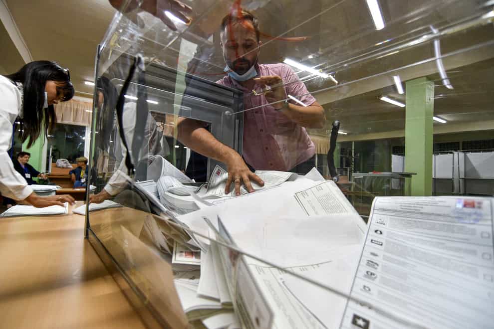 A member of an election commission pulls ballots out of a box preparing to count them at a polling station (AP)