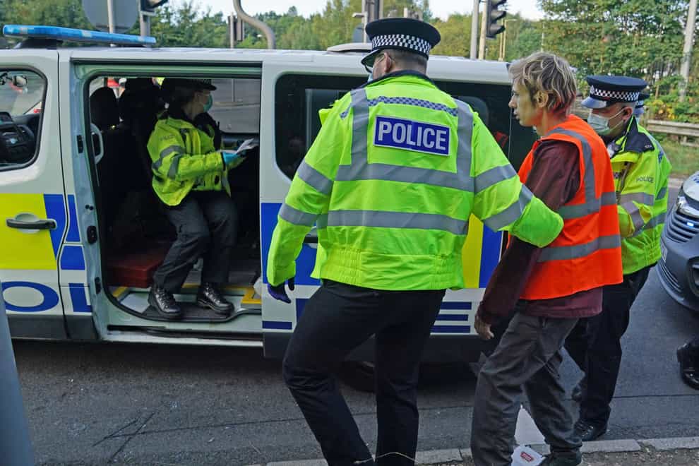 Officers lead a protester to a police van at a slip road at Junction 18 of the M25, near Rickmansworth, where climate protesters carried out a further action after demonstrations which took place last week across junctions in Kent, Essex, Hertfordshire and Surrey. (Steve Parsons/PA)