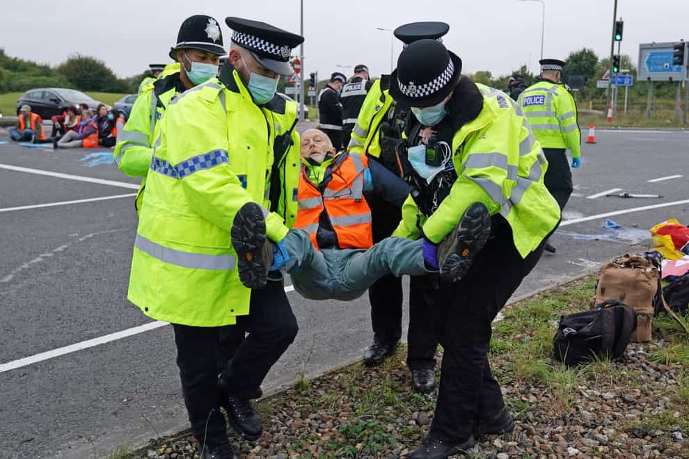 Police officers carry away a protester who had glued himself to the highway at a slip road at Junction 4 of the A1(M), near Hatfield (Steve Parsons/PA)