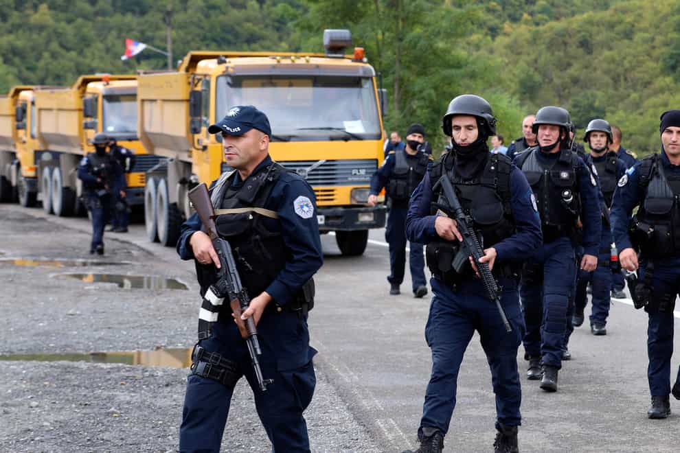 Kosovo police officers patrol by trucks where Kosovo Serbs block a road near the northern Kosovo border crossing of Jarinje, Monday, Sept. 20, 2021. Tensions soared Monday at the border between Kosovo and Serbia as Kosovo deployed additional police to implement a rule to remove Serbian license plates from cars entering Kosovo, while Serbs protested the move. (AP Photo/Bojan Slavkovic)