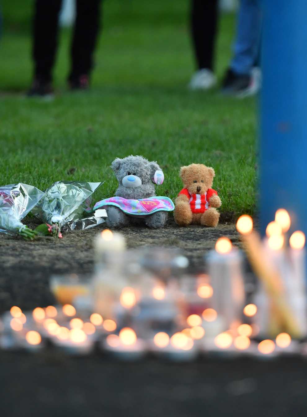 Flowers, soft toys and candles are seen at a vigil at the scene (Anthony Delvin/PA)
