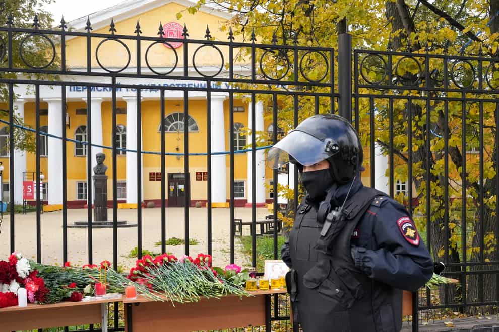A police officer walks past flowers and candles displayed on a table outside the Perm State University following a campus shooting (AP Photo/Dmitri Lovetsky)