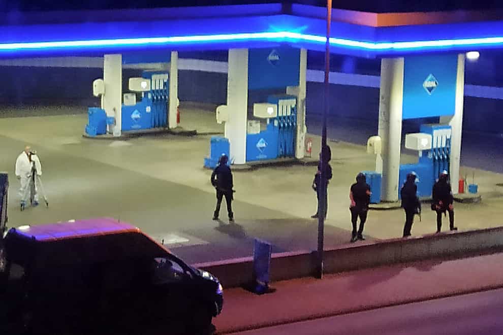Police officers secure a petrol station in Idar-Oberstein, Germany after a man was arrested on suspicion of murder (Christian Schulz/Foto Hosser/dpa via AP)