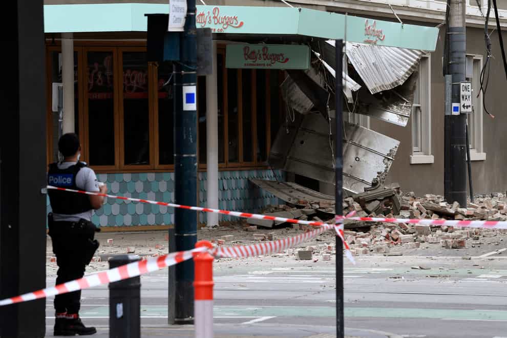 A police officer closes an intersection where debris is scattered in the road after an earthquake damaged a building in Melbourne (James Ross/AAP Image via AP)