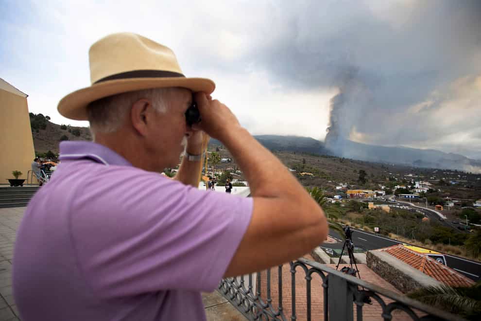 A man looks out towards the eruption of a volcano near El Paso on the island of La Palma in the Canaries, Spain, Monday, Sept. 20, 2021. Lava continues to flow slowly from a volcano that erupted in Spain’s Canary Islands off northwest Africa. Officials say they are not expecting any other eruption and no lives are currently in danger. (AP Photo/Gerardo Ojeda)