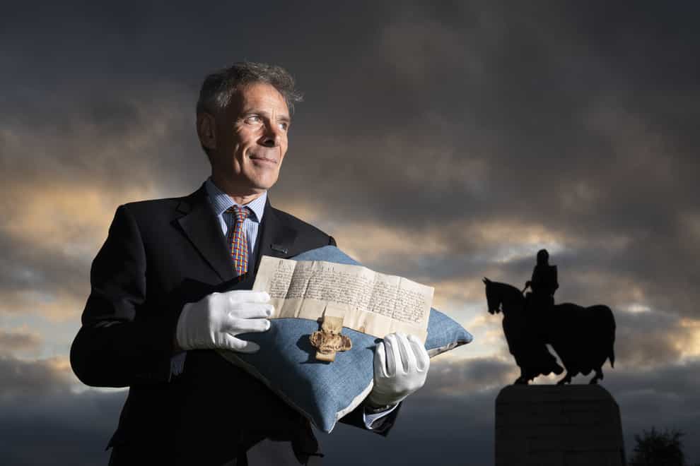 Managing Director of Bonhams Scotland Charles Graham-Campbell holds the Robert the Bruce Letters Patent in his name as King of Scotland alongside the statue of Robert the Bruce at Bannockburn (Jane Barlow/PA)