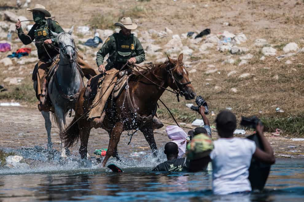US Customs and Border Protection mounted officers attempt to contain migrants as they cross the Rio Grande (AP Photo/Felix Marquez)