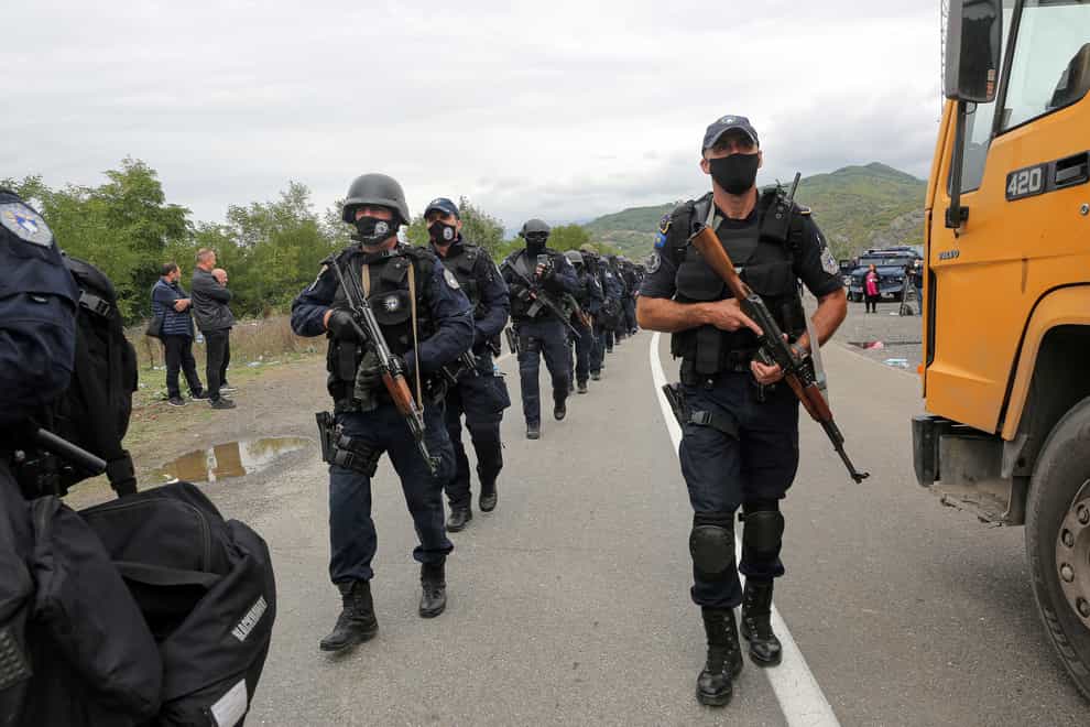Kosovo police officers walk to replace their colleagues near the northern border crossing of Jarinje (Visar Kryeziu/AP)