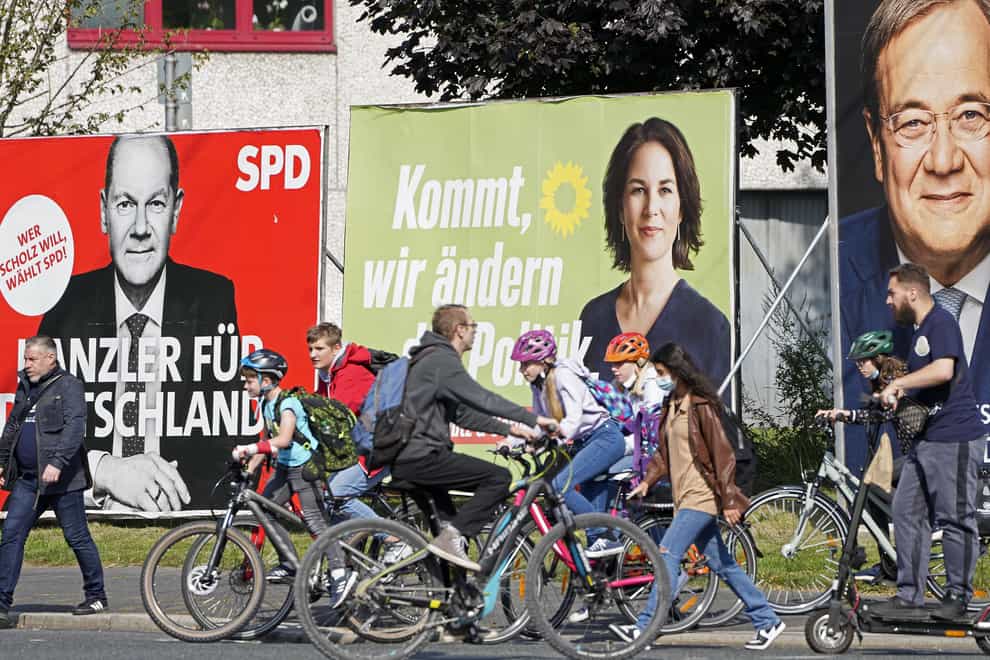 People walk and drive past election posters of the three chancellor candidates, from right, Armin Laschet, Christian Democratic Union (CDU), Annalena Baerbock, German Green party (Die Gruenen) and Olaf Scholz, Social Democratic Party (SPDD) (Martin Meissner/AP)