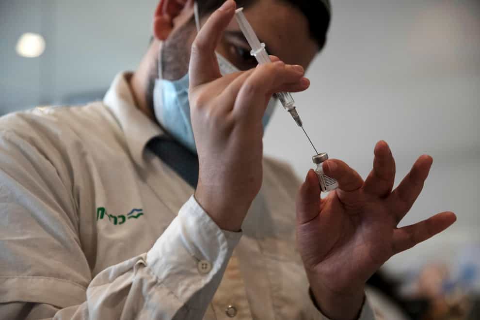A medical worker prepares a vial of the Pfizer coronavirus vaccine at Clalit Health Service’s centre in the Cinema City complex in Jerusalem (AP)