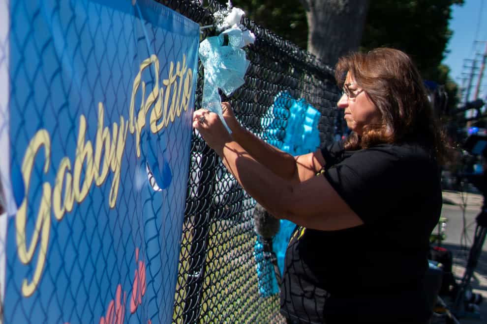 A woman places a decoration near a poster after attending the funeral home viewing of Gabby Petito at Moloney’s Funeral Home in Holbrook, New York (Eduardo Munoz Alvarez/AP)