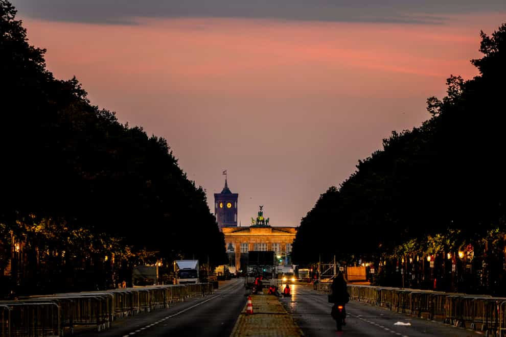 A man rides his bike towards the Brandenburg Gate in Berlin (Michael Probst/AP)