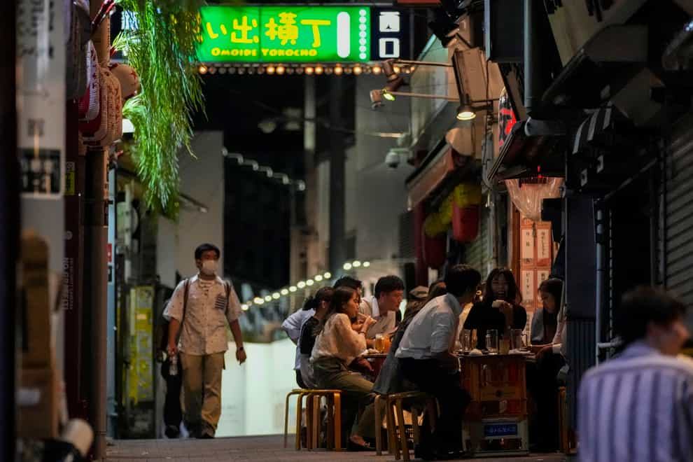 People gather at bars that are open and serving alcohol in Tokyo (Kiichiro Sato/AP/PA)