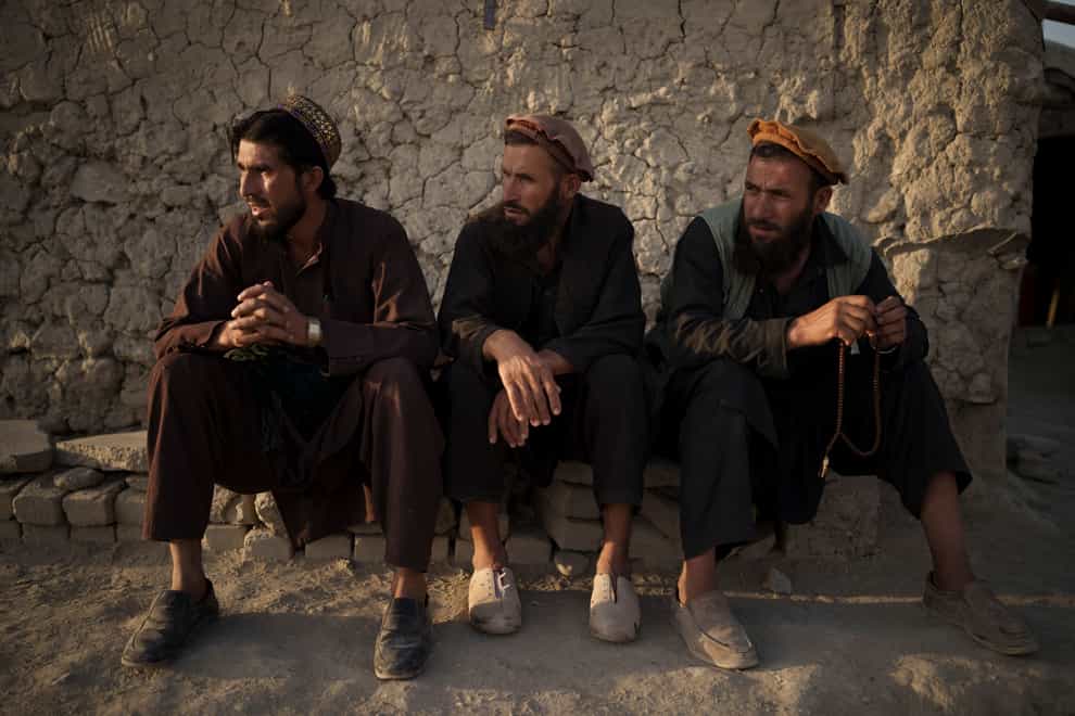 Afghans sit outside a mosque in Kabul on Monday. The Taliban has ordered barbers in one province not to trim or shave beards (Felipe Dana/AP)