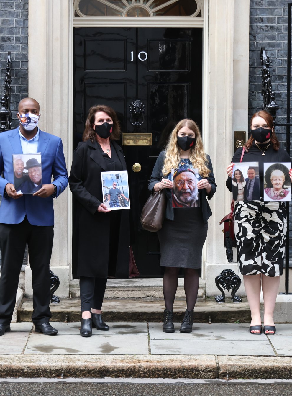 Members of the Covid-19 Bereaved Families for Justice group holding photos of loved ones outside 10 Downing Street, London, after their private meeting with Boris Johnson (James Manning/PA)