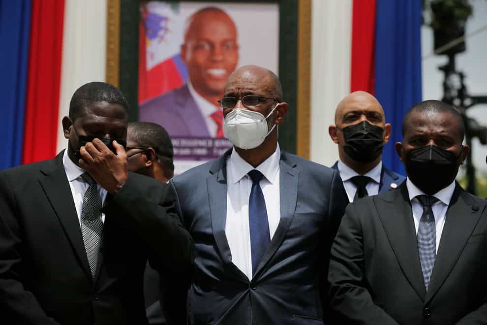 Haiti’s designated prime minister Ariel Henry, centre, and interim prime minister Claude Joseph, right, pose for a group photo with other authorities in front of a portrait of murdered Haitian President Jovenel Moise (Joseph Odelyn/AP)