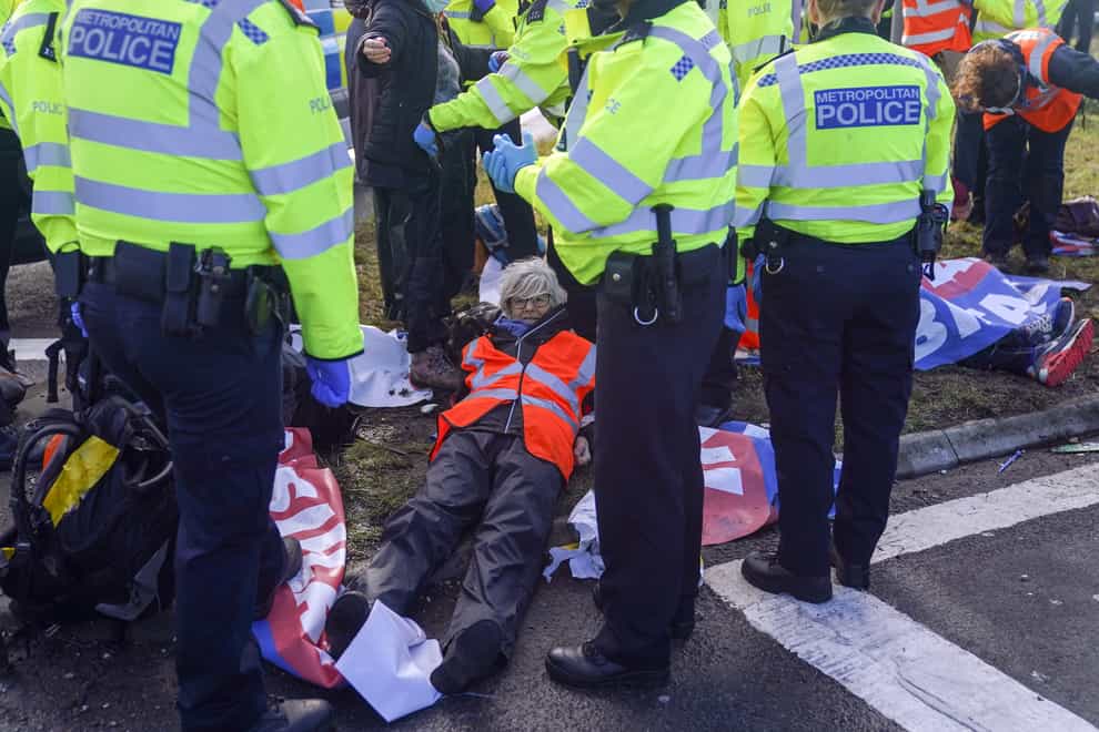 Police officers detain a protester from Insulate Britain occupying a roundabout leading from the M25 motorway (Steve Parsons/PA)