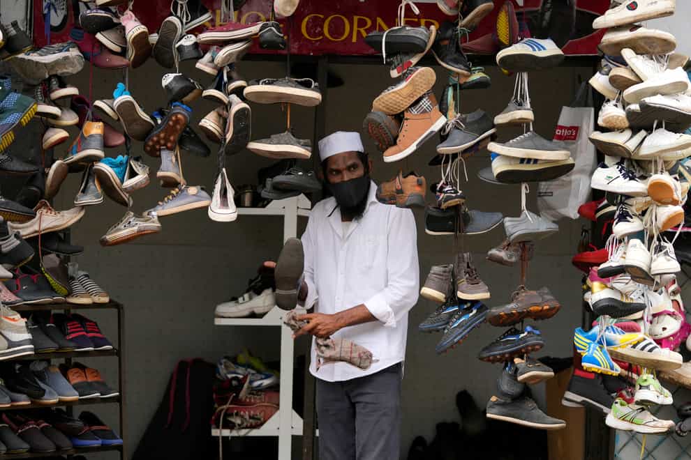 A man om Colombo displays used shoes for sale at his shop after easing of coronavirus restrictions in Colombo, Sri Lanka (Eranga Jayawardena/AP )