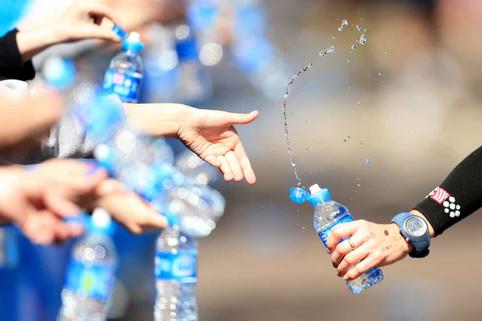 Volunteers offer runners water during the Virgin London Marathon (PA)
