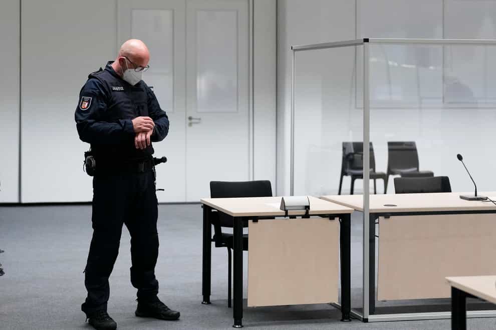 A judicial officer looks at his watch prior to a trial against a 96-year-old former secretary for the SS commander of the Stutthof concentration camp at the court room in Itzehoe, Germany, Thursday, Sept. 30, 2021. The woman who is charged of more than 11,000 counts of accessory to murder has not appeared and is wanted by warrant. (AP Photo/Markus Schreiber, Pool)