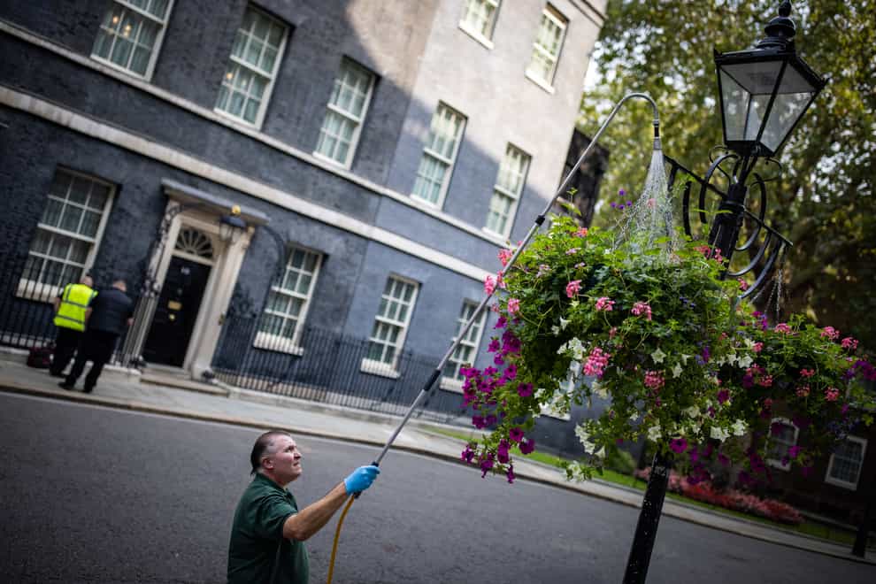 A man waters hanging baskets in Downing Street, London (Aaron Chown/PA)