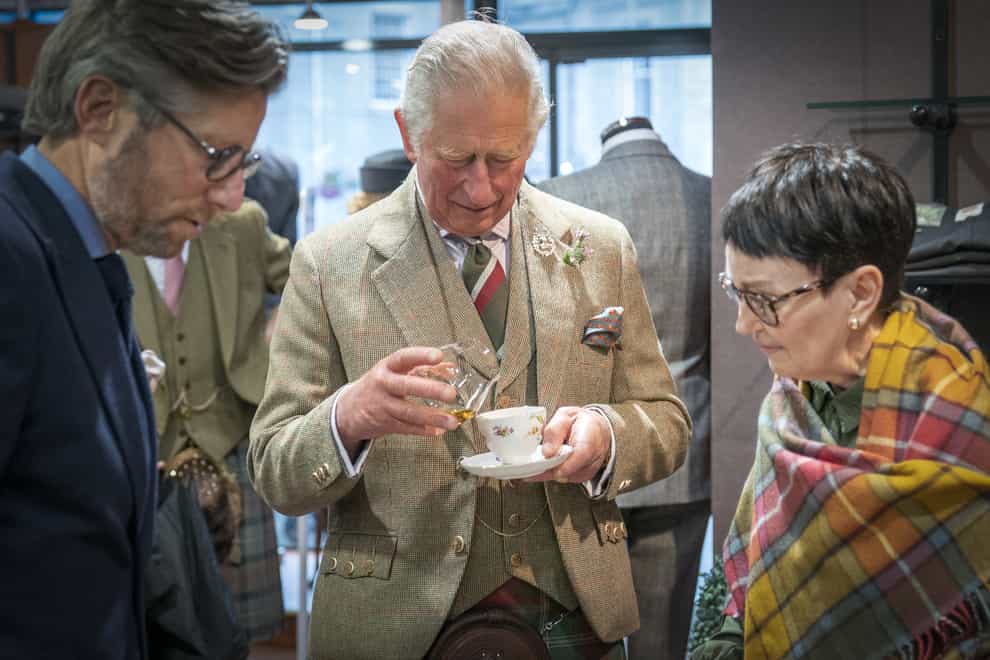 The Duke of Rothesay pours some whisky into his cup of tea at Gibbs – Gentlemen’s Outfitter, Inverurie (Jane Barlow/PA)