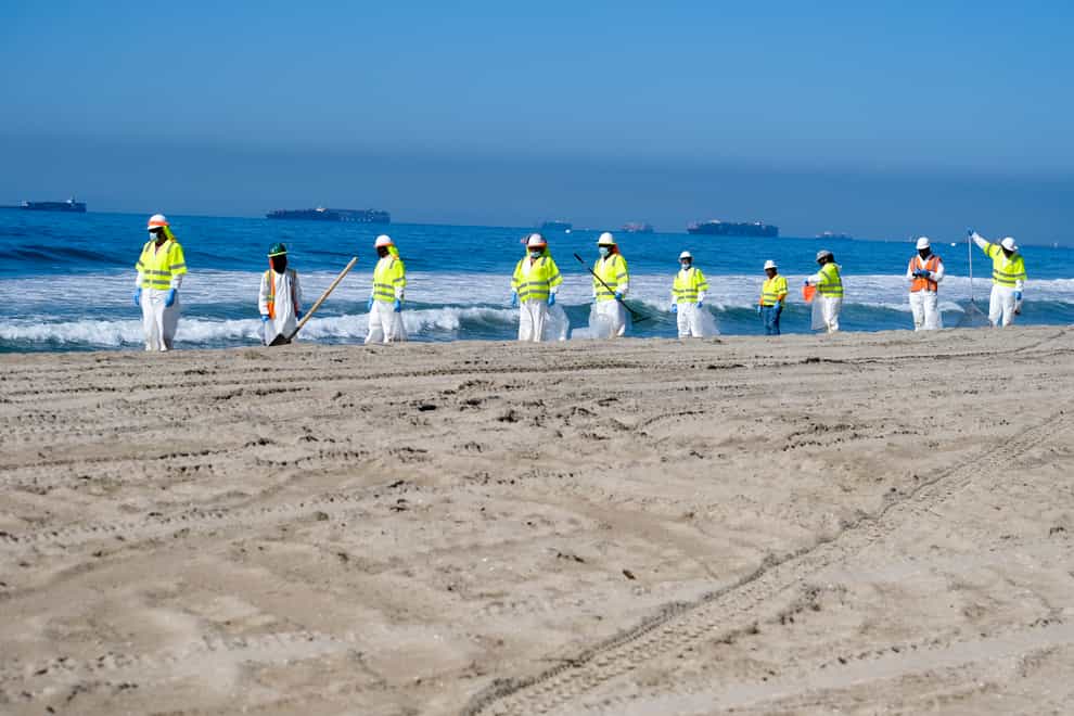 Workers in protective suits clean the contaminated beach after an oil spill in Huntington Beach (Ringo HW Chiu/AP)