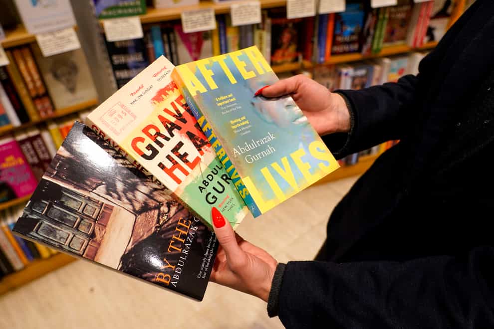 A member of staff holds copies of books by Zanzibar-born novelist Abdulrazak Gurnah in a book shop in London (Alberto Pezzali/AP)