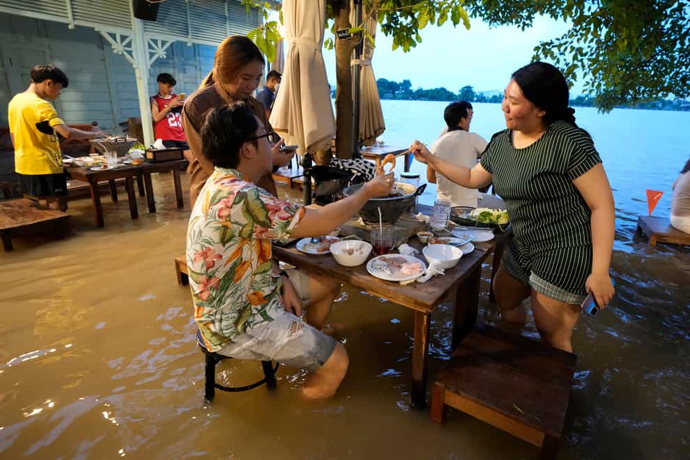 Customers of the riverside Chaopraya Antique Cafe enjoy themselves despite the high water levels in the Chao Phraya River in Nonthaburi, near Bangkok, Thailand (Sakchai Lalit/AP)