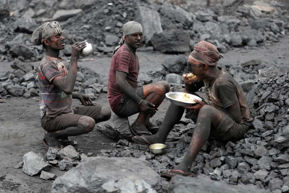 Labourers eat lunch at a coal loading site in the village of Godhar in Jharia (AP)