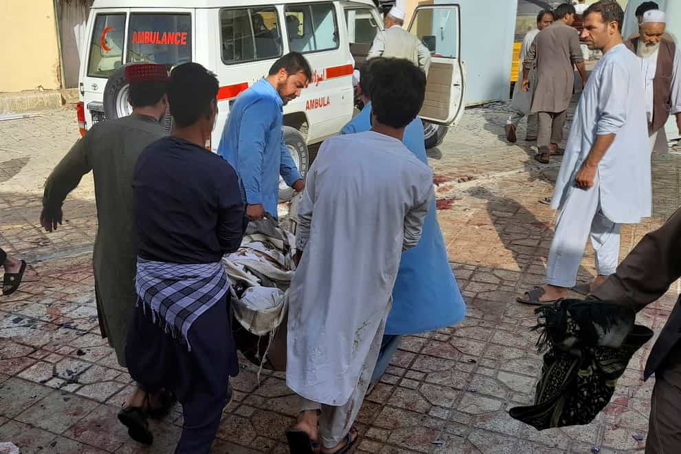 People carry a bombing victim in Kunduz province, northern Afghanistan, Friday, Oct. 8, 2021. A powerful explosion in a mosque frequented by a Muslim religious minority in northern Afghanistan on Friday has left several casualties, witnesses and the Taliban’s spokesman said. (AP Photo/Abdullah Sahil)